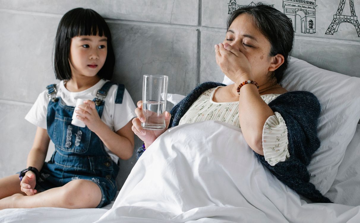 Cucu menemani nenek yang sedang minum obat di rumah